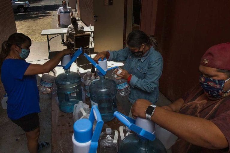 Dorothea Thurby, from left, Britany Archer and Johnson Bill refill empty bottles for a local resident while working at the water distribution site at the Warm Springs Indian Reservation.